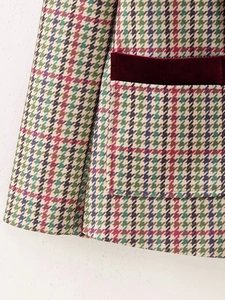 Macro detail of houndstooth weave with wine red velvet trim on a blazer pocket