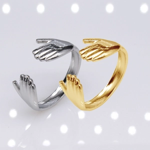 Detailed view of silver and gold hugging hands adjustable rings in stainless steel
