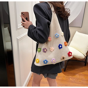 Detail of hand-crocheted cream tote bag with colorful 3D knitted flower accents