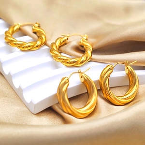 Detail showing gold plated stainless steel twisted hoop earrings on satin fabric
