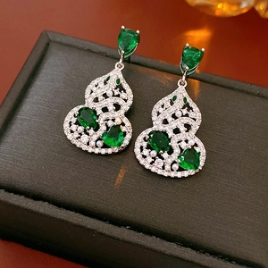 Detail of emerald green stone gourd earrings with pearls on black jewelry box