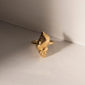 Golden stainless steel seashell ring with ocean texture on a minimalist stone background
