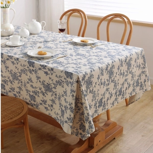 Detail of blue pattern on beige linen blend tablecloth spread on a wooden table