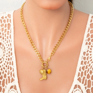 Macro view of gold stainless steel necklace with sun, boot and gemstone charms