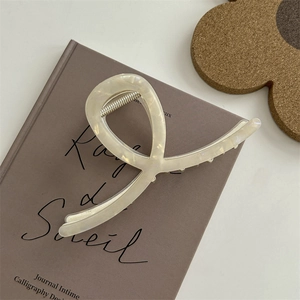 Pinza per capelli bianco crema trasparente dal design aerodinamico su sfondo minimale