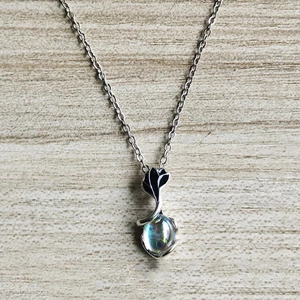 Close-up of a moonstone pendant on a silver chain over a natural wood texture