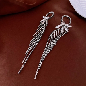 Macro shot of silver bow tassel earrings with sparkling rhinestones on dark leather