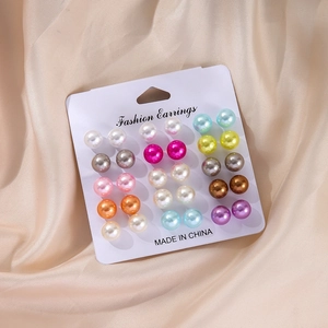 Detailed view of 12 pairs of colorful pearl stud earrings set on a white fashion card