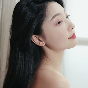 Close-up of elegant gold heart-shaped stud earring with crystals on model's ear