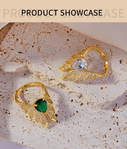 Close-up of wings ring set with emerald and white zircon stones on stone background