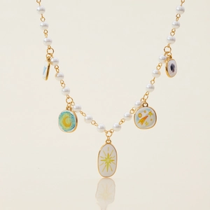 Collier de perles avec breloques dorées lune et étoiles sur surface réfléchissante