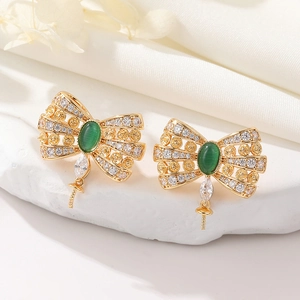 Macro detail of golden bow earrings with green cat-eye stone and crystal butterfly wings