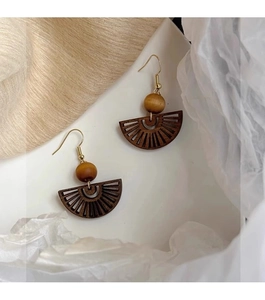 Detail of retro wooden fan earrings with beads and golden hooks on white silk backdrop