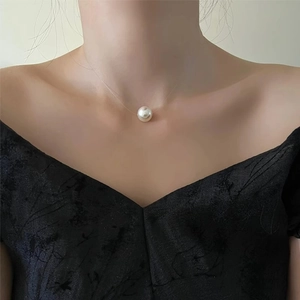 Close-up of a minimalist floating pearl pendant on a thin transparent fishing line necklace