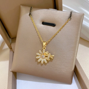 Close-up of a gold daisy and dragonfly necklace with crystal accents in a jewelry box