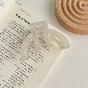 Detail of white acetate hair claw clip with France Handmade gold lettering on a book