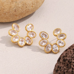 Detail of 18K gold plated flower earrings with oval zircons on natural stone background