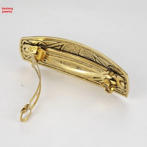 Detailed side view showing antique gold spring hair clip with embossed floral metal patterns