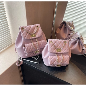 Close-up of quilted dark purple backpack set with gold chain and metal buckle details
