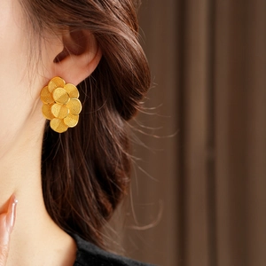 Détail de boucles d'oreilles fleur plaquées or 18 carats portées par un mannequin chic