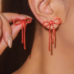 Macro shot of sparkling red rhinestone bow earrings with delicate tassel drop details