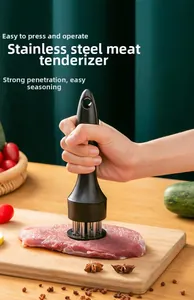Manual stainless steel meat tenderizer tool pressing on fresh steak in a kitchen