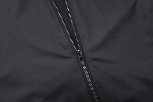 Macro shot of silver metal zipper detail on black long sleeve hoodie fabric texture