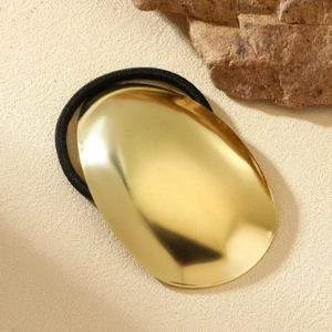 Minimalist gold oval metal hair tie with black high elasticity band on stone base