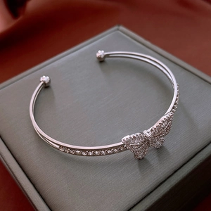 Detailed close-up of a silver butterfly open bangle with pave-set zircons on silk