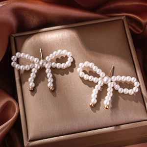 Detail view of pearl bow earrings with gold tassels on vintage bronze jewelry box