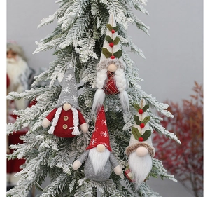Detail view of four Christmas gnomes hanging on a snowy tree with knitted hats and beards