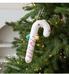 Christmas candy cane ornament hanging on a Christmas tree with festive warm lighting
