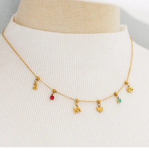 Golden necklace with 18K charms like letter M and number 2 displayed on a mannequin neck
