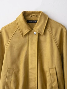 Detailed view of the yellow faux suede texture and metallic button pockets on the bomber jacket