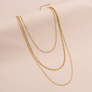 Detail of layered gold necklace featuring Figaro chains and a sleek flat snake chain