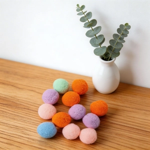 Pompons en feutre colorés pour chats sur une surface en bois au style minimaliste