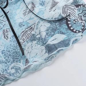 Detailansicht eines blau geblümten Netzhose-Tops mit schwarzem Band und Wellensaum-Detail