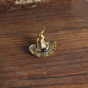 Macro shot of a vintage gold wizard hat brooch with small rhinestones and a black gemstone