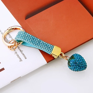 Sparkling blue rhinestone heart keychain with gold hardware on a book backdrop