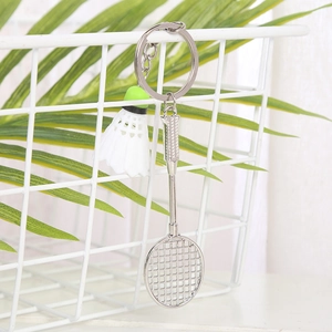 Detailed shot of miniature silver badminton racket and shuttlecock on a metal keychain