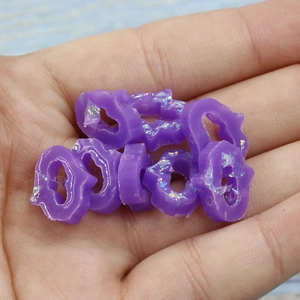 Detailed close-up of purple resin cat head charms with iridescent glitter for DIY jewelry