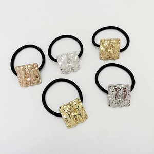 Detail of five gold and silver textured square metal hair ties on white background