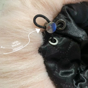 Detail of adjustable metal buckle and pink faux fur trim on a black quilted winter hat