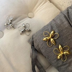 Detailed macro view of stylish large metallic clover flower earrings in gold and silver
