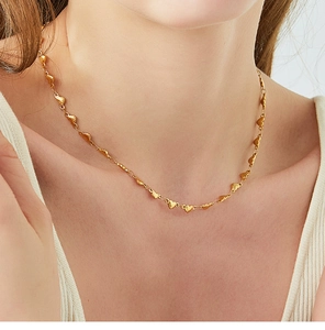 Detailed view of an 18K gold plated necklace with small heart pendants on a model's neck