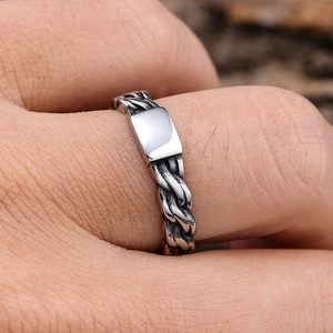Close-up of silver punk style flame totem ring with woven texture and rectangle plaque