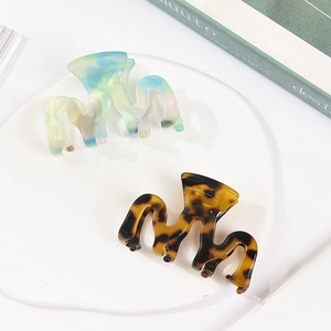 Elegant wave-shaped acetate hair claws in colorful gradient and classic tortoiseshell finish