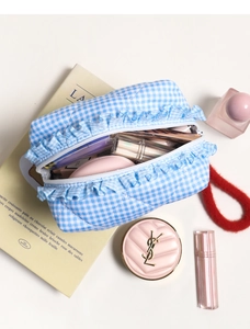 Detailed top view of light blue checkered makeup bag with feminine lace trim and cosmetics