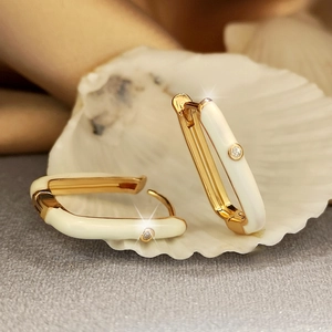 Macro view of gold hoop earrings with white enamel and a sparkling center zircon