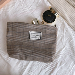 Detail of vintage plaid toiletry bag with brown tartan pattern and fabric logo label